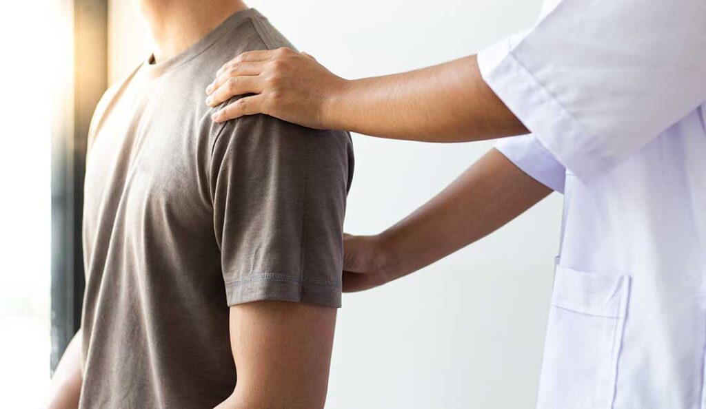 Patient discusses back pain and medical history with a chiropractor in a bright examination room.