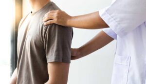 Patient discusses back pain and medical history with a chiropractor in a bright examination room.